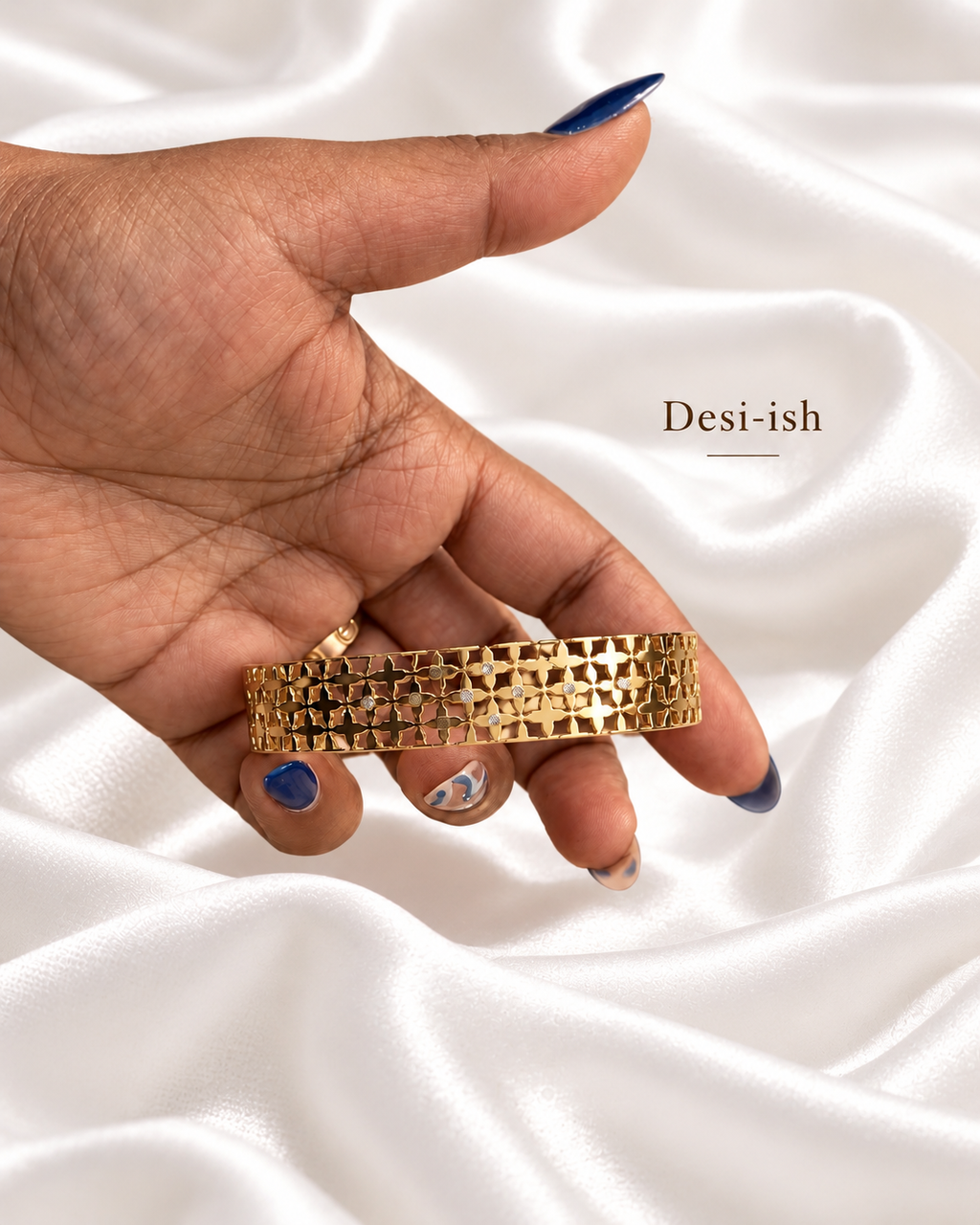 Quatrefoil crystal gold-tone kada held in hand on white satin